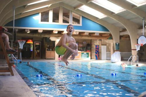 a young boy jumping into a swimming pool at Seven Springs 2BRLoft Premium Condo, sleeps 11! condo in Champion