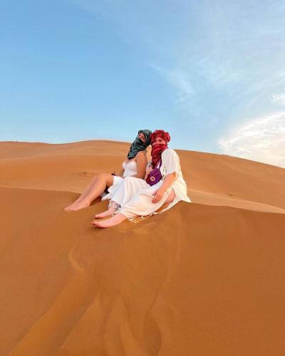 a couple laying on a sand dune in the desert at Merzouga luxury magic nights in Merzouga
