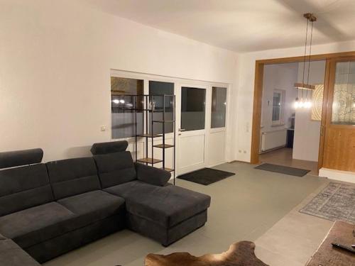 a living room with a gray couch and a living room with a kitchen at Seenahes Haus mit Hot Tub in Krumpendorf am Wörthersee