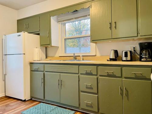 cocina con armarios verdes y nevera blanca en Central Chic on Washington, en Evansville