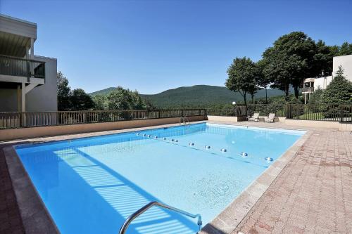 a large blue swimming pool with mountains in the background at Notchbrook 28AB in Stowe