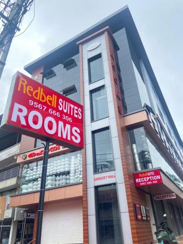 a building with a red sign in front of it at Redbell Suites Kizhisseri in Kondotti