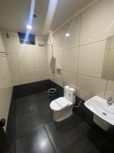 a bathroom with a white toilet and a sink at Redbell Suites Kizhisseri in Kondotti