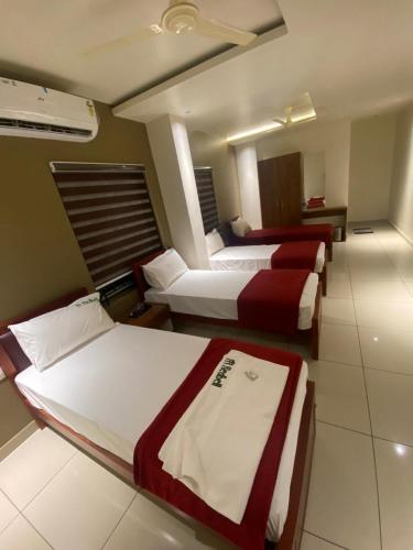 a hotel room with three beds in a row at Redbell Suites Kizhisseri in Kondotti
