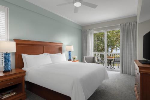 um quarto com uma grande cama branca e uma varanda em Marriott's Harbour Club em Hilton Head Island