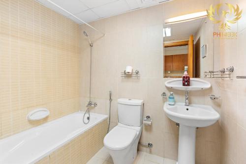 y baño con aseo, lavabo y bañera. en Phineek Homes Elegant Studio Lake Side IMPZ Production City, en Dubái