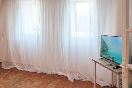 ein Wohnzimmer mit Fernseher und Fenster in der Unterkunft FilinHome Trg Mladenaca in Novi Sad