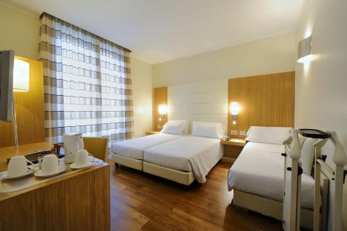 a hotel room with two beds and a desk at Hotel Canada in Milan