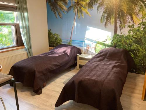 two beds in a room with palm trees on the wall at Revontuli Apartments in Rovaniemi