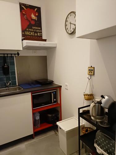 une cuisine avec un micro-ondes et une horloge au mur dans l'établissement Pause nature au cœur du parc naturel du Médoc, à Moulis-en-Médoc