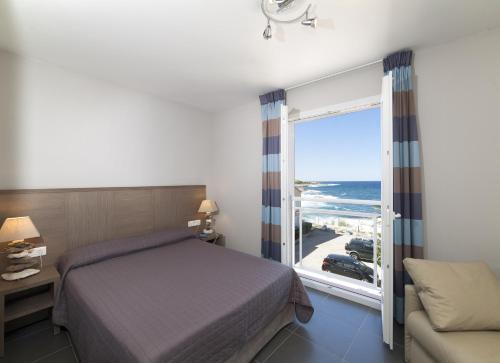 a bedroom with a bed and a view of the ocean at Hotel St Joseph in Algajola