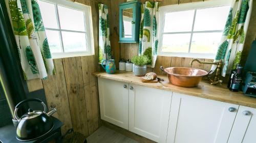a kitchen with a sink and two windows at Ynys Hideout in Moelfre