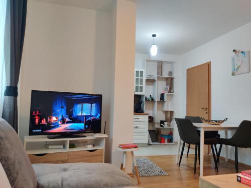 un soggiorno con TV e tavolo con sedie di Cozy near City Center Apartment! a Pristina