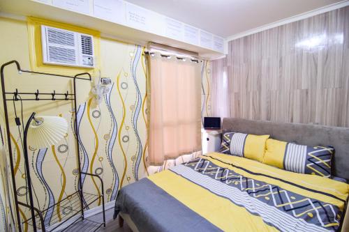 a bedroom with a bed with yellow and blue at GoldMine Staycation in Manila