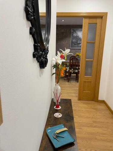 a table with a vase of flowers and a mirror at Apartamento Ronda San Antón in Toro