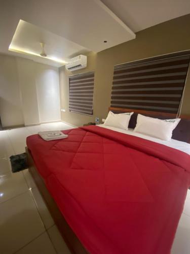 a large red bed with white pillows in a room at Redbell Suites Kizhisseri in Kondotti