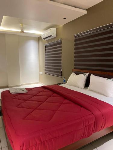 a bedroom with a large bed with a red blanket at Redbell Suites Kizhisseri in Kondotti
