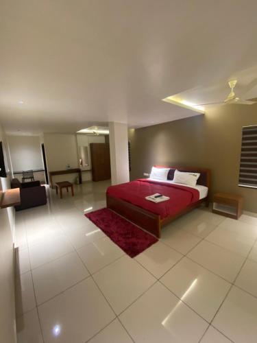 a bedroom with a red bed and a living room at Redbell Suites Kizhisseri in Kondotti