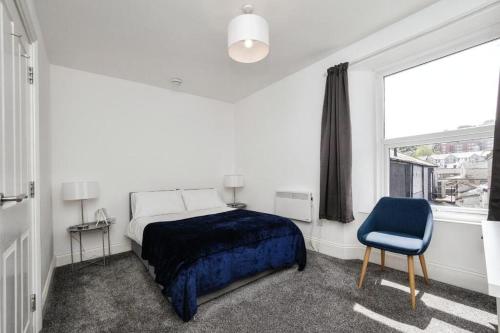 a bedroom with a bed and a blue chair at 3- Bedroom modern,spacious apartment-Devon in Newton Abbot