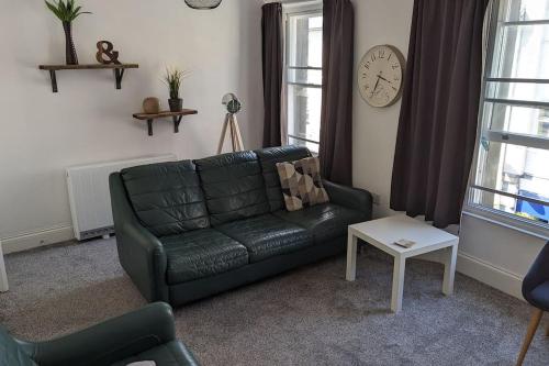 a living room with a green couch and a clock at 3- Bedroom modern,spacious apartment-Devon in Newton Abbot
