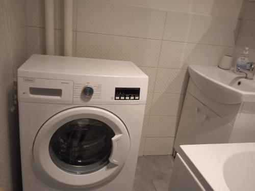 uma máquina de lavar roupa branca numa casa de banho ao lado de um lavatório em U Cioci em Cracóvia