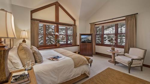 een slaapkamer met een bed, een stoel en ramen bij Chalet Premio in Beaver Creek