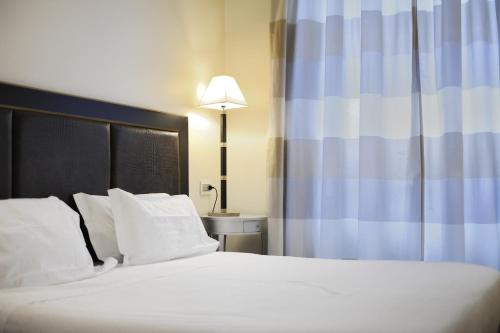a bedroom with a bed with white pillows and a lamp at Hotel Canada in Milan