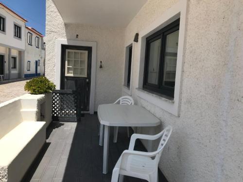 einen weißen Tisch und Stühle auf einer Terrasse mit einem Fenster in der Unterkunft Casa da Ilha do Baleal in Baleal