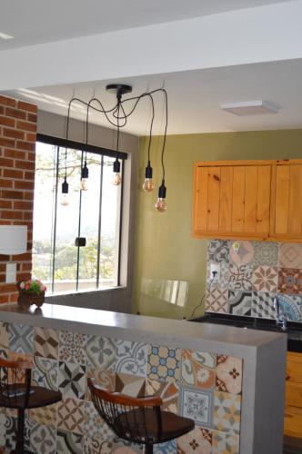 a kitchen with a counter with chairs and a window at Chalés Estrada Real in Conceição da Ibitipoca
