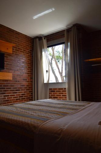 a bedroom with a bed and a window at Chalés Estrada Real in Conceição da Ibitipoca
