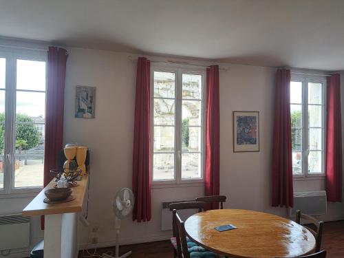 een eetkamer met een tafel en twee ramen bij Loft vue imprenable sur le vieux Saintes in Saintes