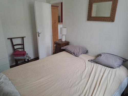 een slaapkamer met een bed met 2 kussens en een spiegel bij Loft vue imprenable sur le vieux Saintes in Saintes