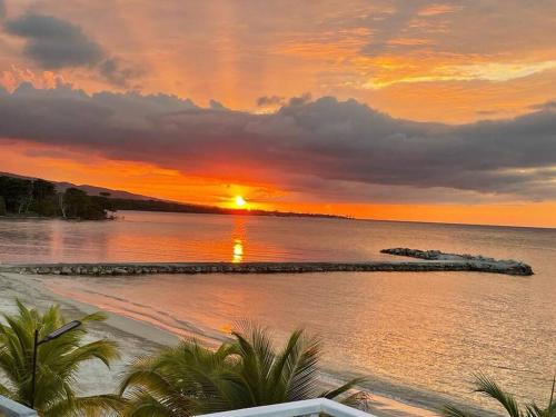 un tramonto sull'acqua con una spiaggia di serendipity on the beach Ocho Rios a Saint Annʼs Bay