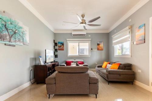 a living room with two couches and a ceiling fan at serendipity on the beach Ocho Rios in Saint Annʼs Bay