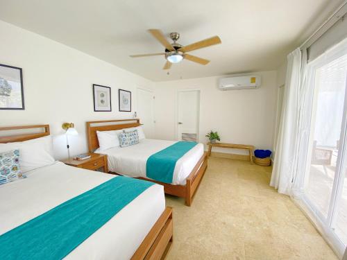 a bedroom with two beds and a ceiling fan at Xeliter Green One Playa Dorada in San Felipe de Puerto Plata