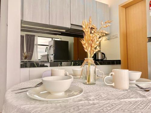 a table with plates and cups and a vase with flowers at imperium residence kuantan in Kuantan