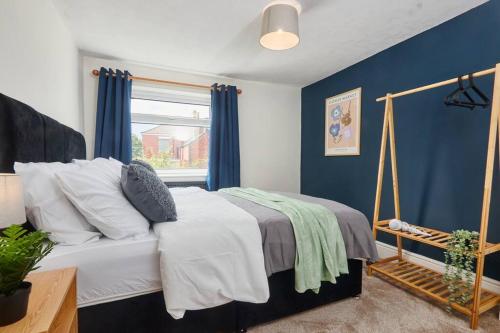 una camera da letto con un letto con pareti blu e una finestra di Comfortable house by the coast a Redcar