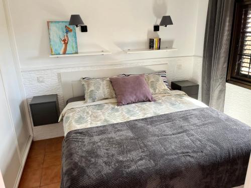 una camera da letto con un letto con un piumone grigio di Bungalow near Yumbo a Playa del Ingles