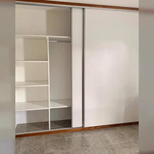 un armario con estanterías blancas y una puerta de cristal en Margarita Tempo en Esquel