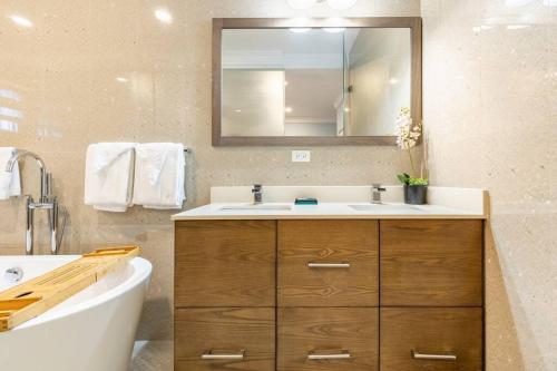 a bathroom with a sink and a mirror and a tub at serendipity on the beach Ocho Rios in Saint Annʼs Bay