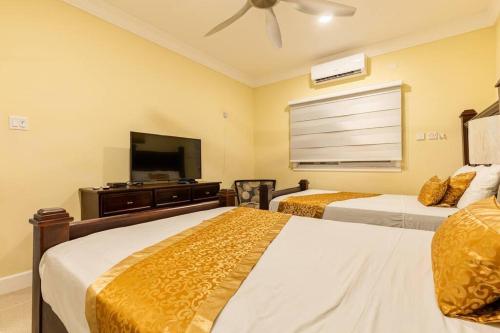 a bedroom with two beds and a flat screen tv at serendipity on the beach Ocho Rios in Saint Annʼs Bay
