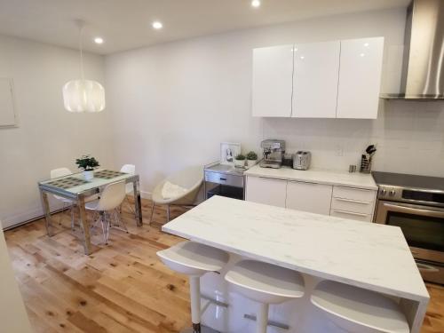 a kitchen with white cabinets and a table and chairs at 3 bedroom near Olympic Stadium in Montréal