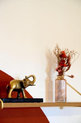 a shelf with a statue of an elephant and a vase of flowers at Calais Plage-Gare Appartement élégant tout équipé in Calais