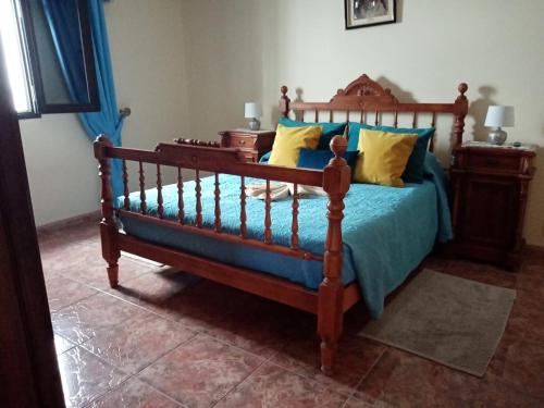 1 dormitorio con cama de madera con sábanas azules y almohadas amarillas en LAMI, en Las Playitas