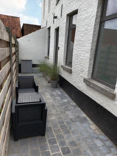 un patio avec deux bancs à côté d'un bâtiment dans l'établissement DE LANDSHOEVE vakantiewoningen, à Zwalm