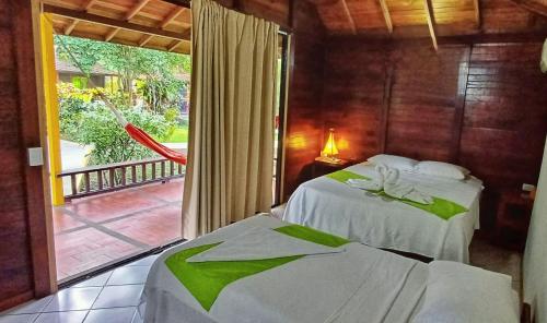 two beds in a room with a view of a porch at Tacarcuna Lodge in Capurganá