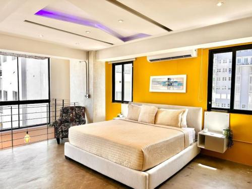 1 dormitorio con cama y pared amarilla en New Loft Apt Full AC King Bed, en Santo Domingo