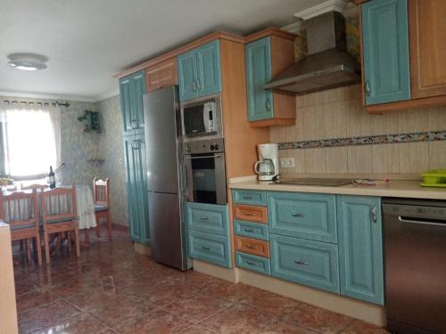 a kitchen with blue cabinets and a kitchen with a table at LAMI in Las Playas