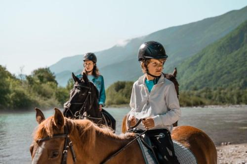 two people are riding horses in the water at Residence Soča in Soča