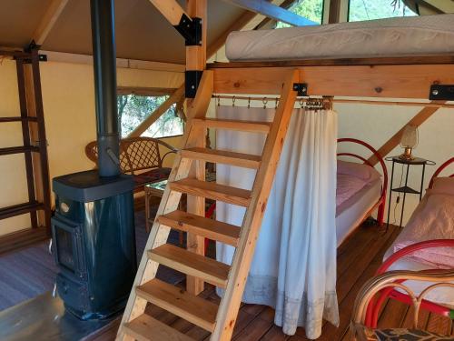 a bunk bed and a ladder in a room with a stove at Glamping tent nel Supramonte in Urzulei